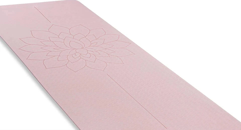 Le tapis de yoga rose déroulé en diagonale, le lotus et la ligne d’alignement gravés visibles sur toute sa longueur.